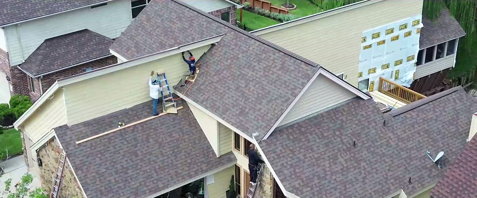 Aerial view of the crew working on the roofline of the Lake Conroe home during the exterior remodel